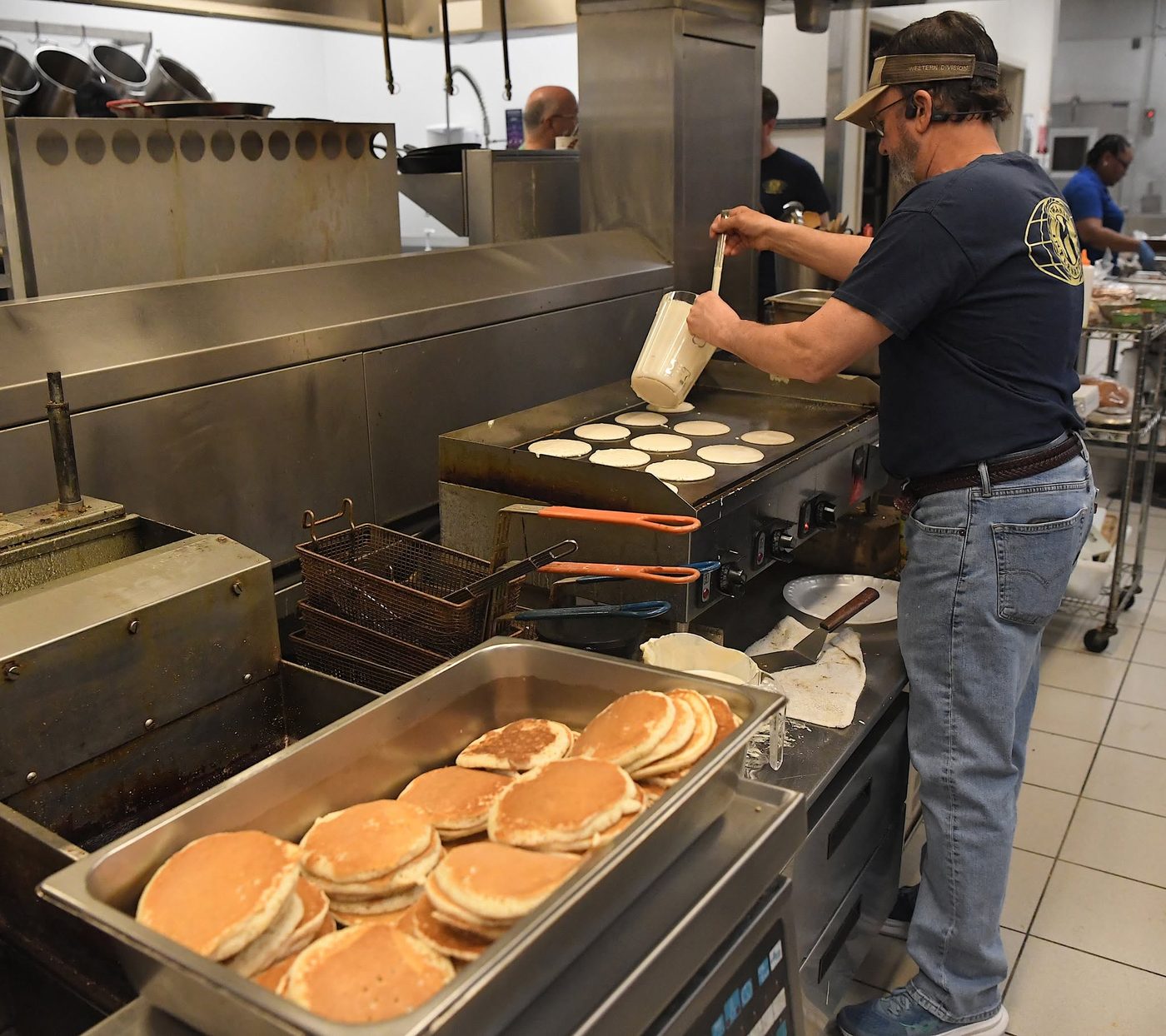 A Kiwanis member cooking pancakes on a griddle